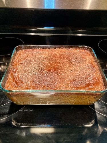 Jamaican cornmeal pudding recipe right out of the oven sitting on a stovetop.