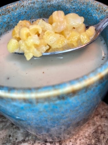 Panamanian chicheme drink with hominy corn displayed on a spoon.