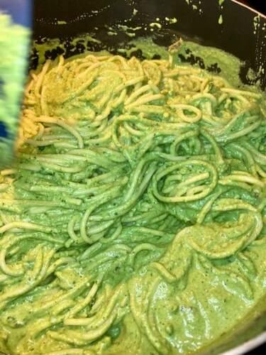 Peruvian green pasta being stirred in a pot.