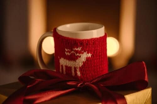 Coffee cup next to a present with a red ribbon representing Christmas coffee drinks.